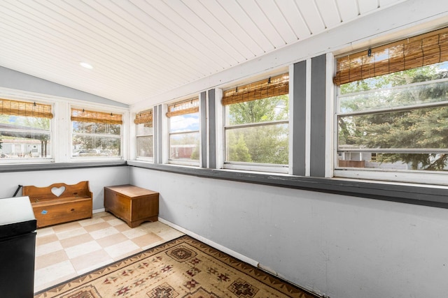 unfurnished sunroom with baseboards, plenty of natural light, tile patterned floors, and lofted ceiling
