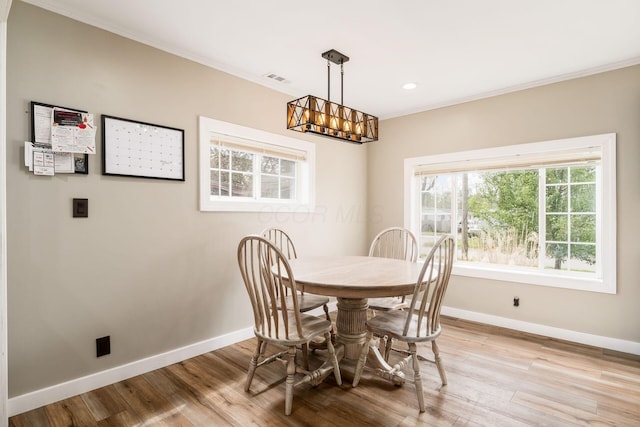dining space featuring an inviting chandelier, baseboards, ornamental molding, and light wood finished floors