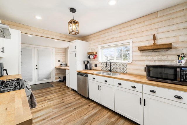kitchen with a sink, white cabinets, light wood-style floors, wood counters, and stainless steel appliances