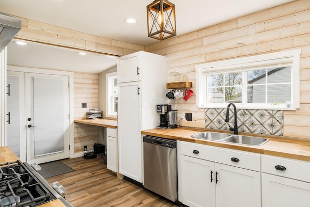 kitchen featuring a sink, stainless steel dishwasher, wooden counters, and white cabinetry