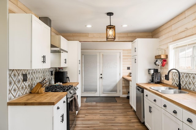 kitchen with appliances with stainless steel finishes, a sink, white cabinets, butcher block counters, and recessed lighting