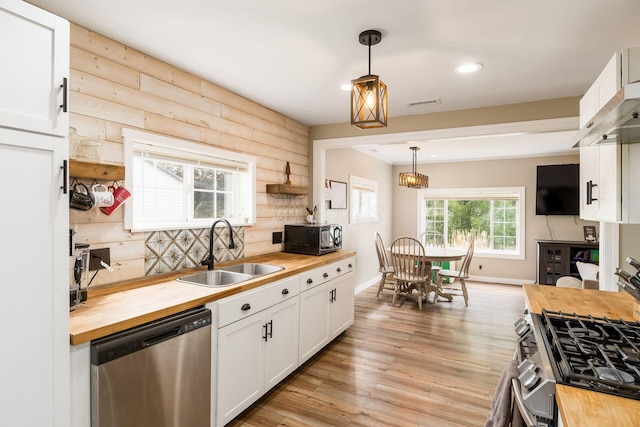 kitchen featuring stainless steel dishwasher, black microwave, wooden counters, and a sink