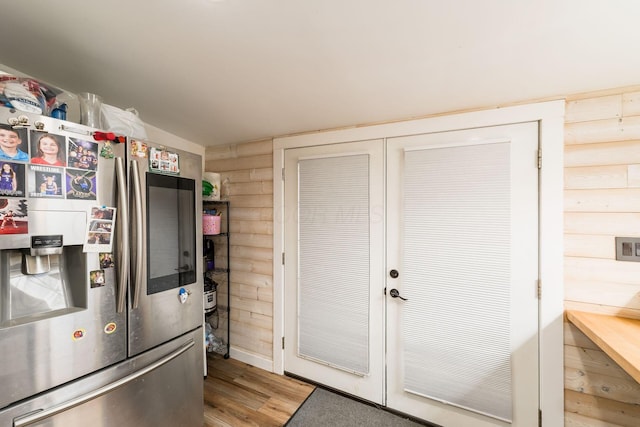 kitchen featuring rustic walls, wood finished floors, and stainless steel fridge with ice dispenser