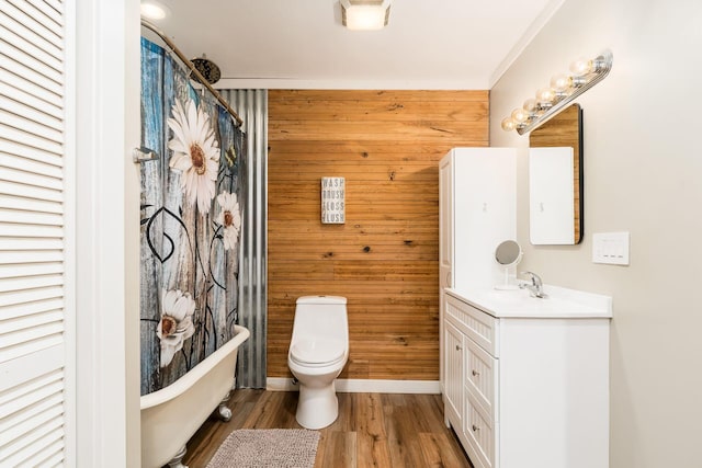 full bathroom with wooden walls, vanity, toilet, wood finished floors, and a soaking tub