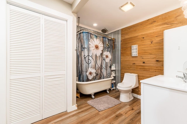 full bath with wood walls, wood finished floors, toilet, a freestanding bath, and a shower with curtain