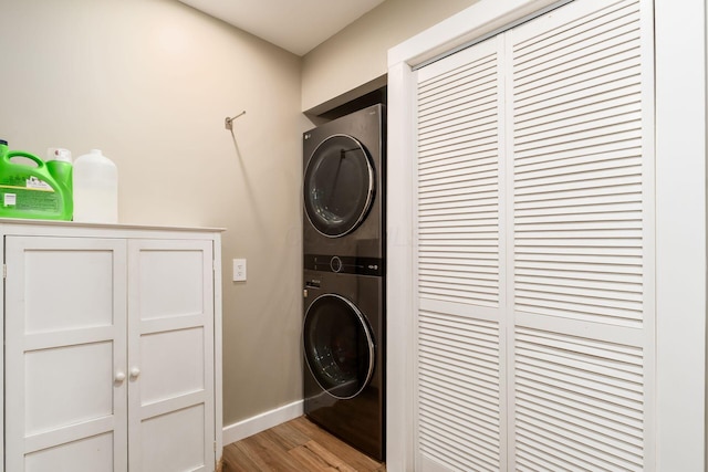 washroom featuring baseboards, laundry area, light wood-style flooring, and stacked washer / dryer