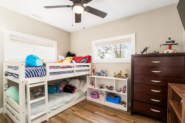 bedroom with ceiling fan, visible vents, and wood finished floors