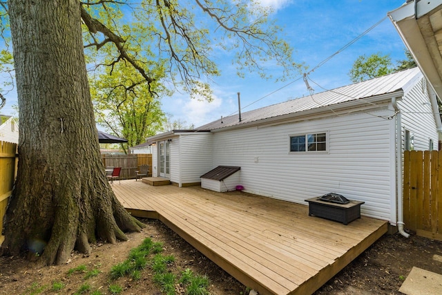 back of house featuring metal roof, a wooden deck, and a fenced backyard