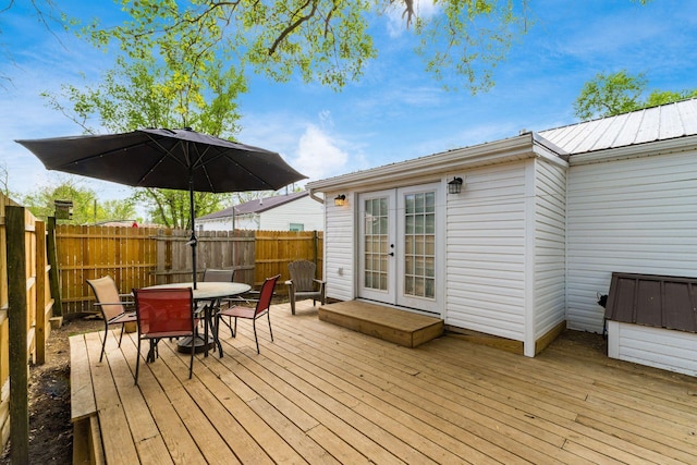 wooden terrace featuring french doors, outdoor dining area, and a fenced backyard