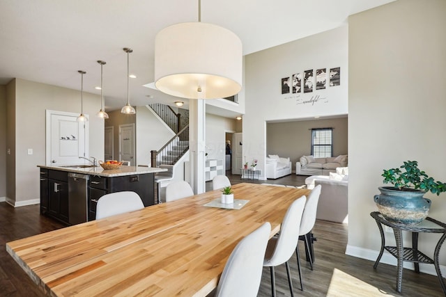 dining space featuring dark wood-style flooring, recessed lighting, baseboards, a towering ceiling, and stairway