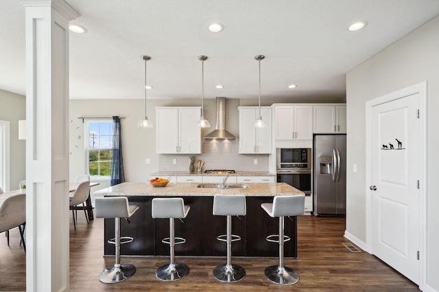 kitchen featuring dark wood-style flooring, wall chimney range hood, stainless steel fridge, built in microwave, and a sink