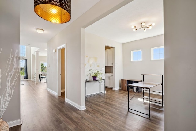hall featuring an inviting chandelier, baseboards, dark wood-type flooring, and a wealth of natural light