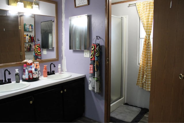 bathroom featuring double vanity, a shower stall, and a sink