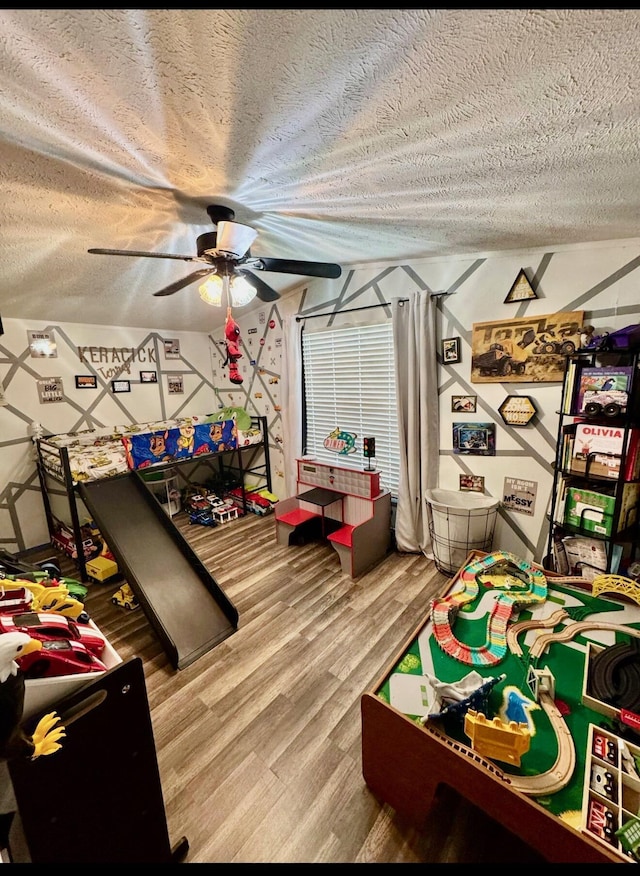 rec room featuring a ceiling fan, a textured ceiling, and wood finished floors