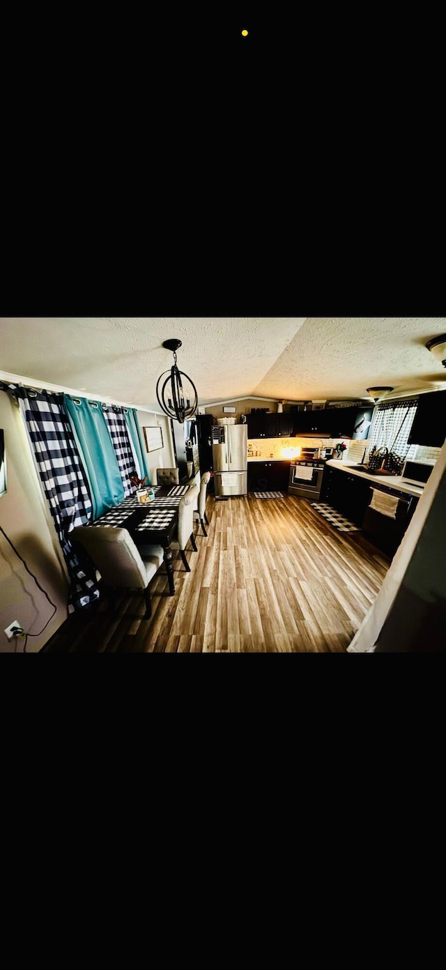 interior space with freestanding refrigerator, a textured ceiling, and wood finished floors