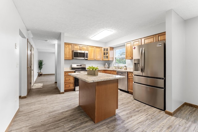 2257 Jarrow Dr, Hilliard, OH 43026 - kitchen with appliances with stainless steel finishes, light wood-style flooring, a center island, baseboards, and glass insert cabinets