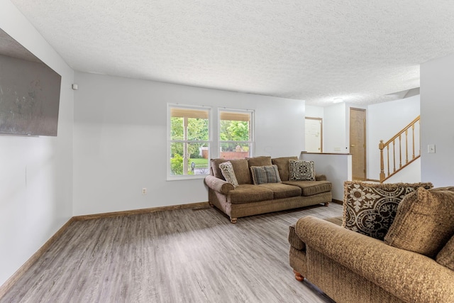 2257 Jarrow Dr, Hilliard, OH 43026 - living room featuring light wood-type flooring, a textured ceiling, baseboards, and stairs