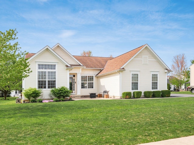 ranch-style house featuring a patio, a shingled roof, and a front lawn