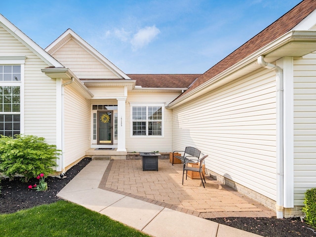 property entrance featuring a patio and roof with shingles