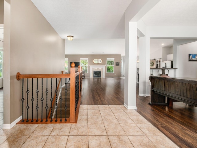 corridor featuring baseboards, wood finished floors, and an upstairs landing
