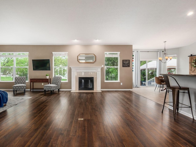 living room with a wealth of natural light, dark wood-style floors, and a notable chandelier