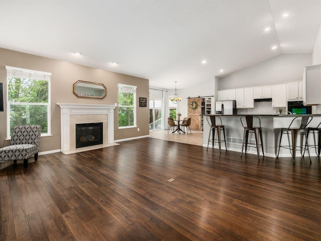 living area featuring wood finished floors, a chandelier, lofted ceiling, recessed lighting, and a premium fireplace