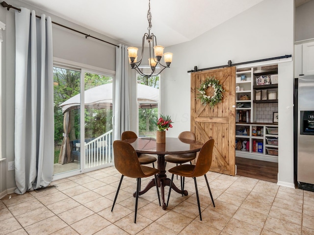 dining space featuring a notable chandelier, a barn door, and light tile patterned floors