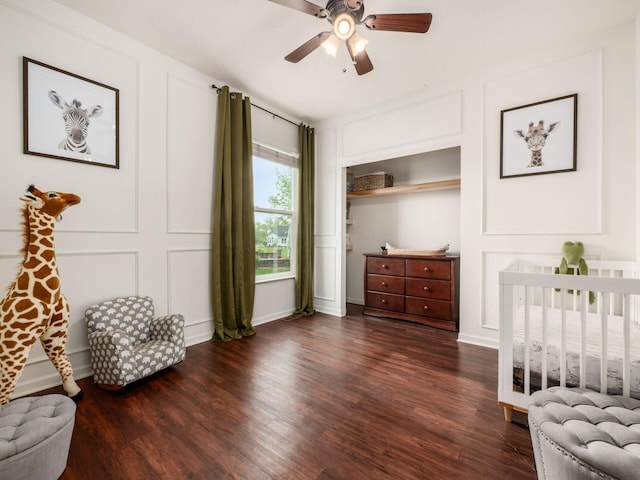 bedroom featuring a ceiling fan, a decorative wall, and wood finished floors