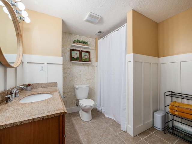 bathroom featuring visible vents, wainscoting, a decorative wall, and toilet
