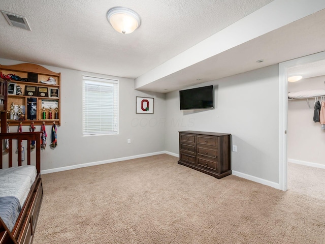 unfurnished bedroom with visible vents, a textured ceiling, and carpet