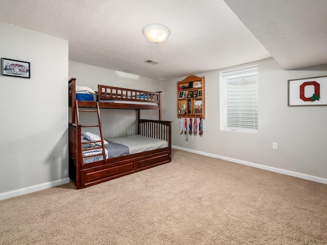 bedroom featuring visible vents, a textured ceiling, carpet, and baseboards