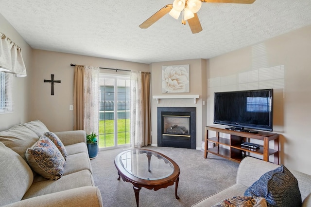 living area with a glass covered fireplace, carpet, a ceiling fan, and a textured ceiling