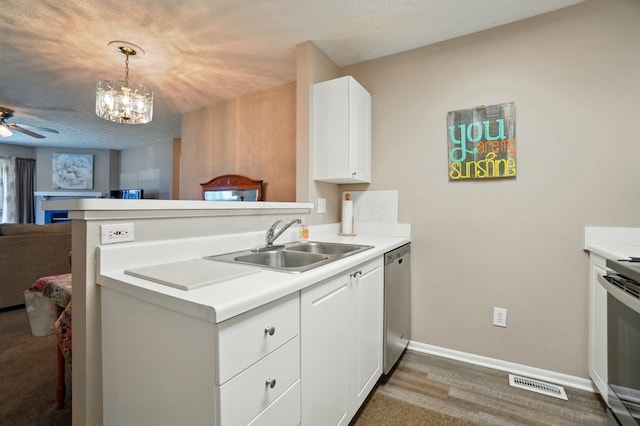 kitchen featuring visible vents, a peninsula, open floor plan, a sink, and stainless steel appliances