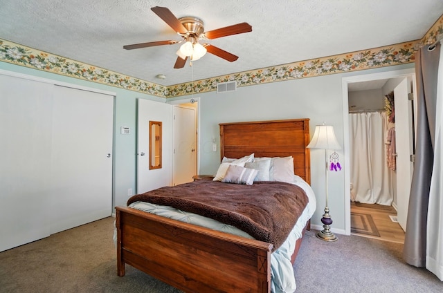 bedroom featuring carpet flooring, a textured ceiling, a ceiling fan, visible vents, and a closet