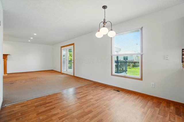 empty room featuring light wood-type flooring, recessed lighting, baseboards, and a chandelier