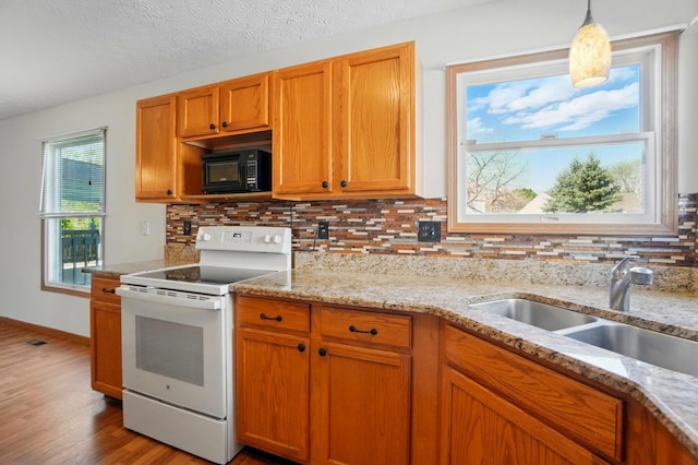 kitchen featuring backsplash, black microwave, wood finished floors, and electric stove