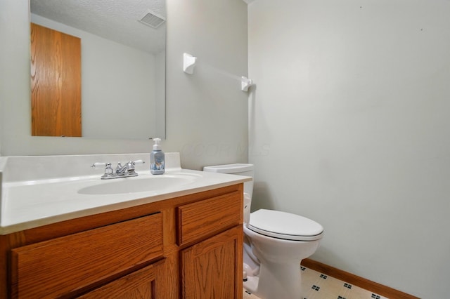 half bath featuring toilet, baseboards, visible vents, and vanity