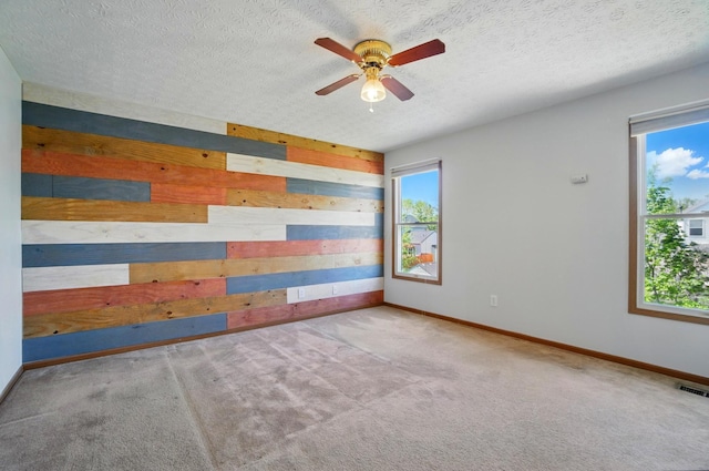 spare room with ceiling fan, wood walls, carpet, baseboards, and visible vents