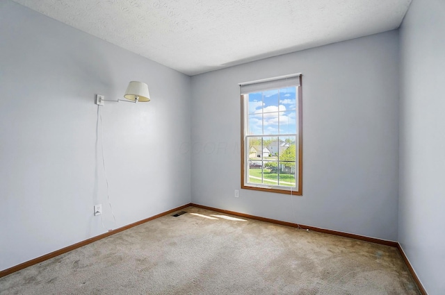 carpeted empty room featuring baseboards, a textured ceiling, and visible vents