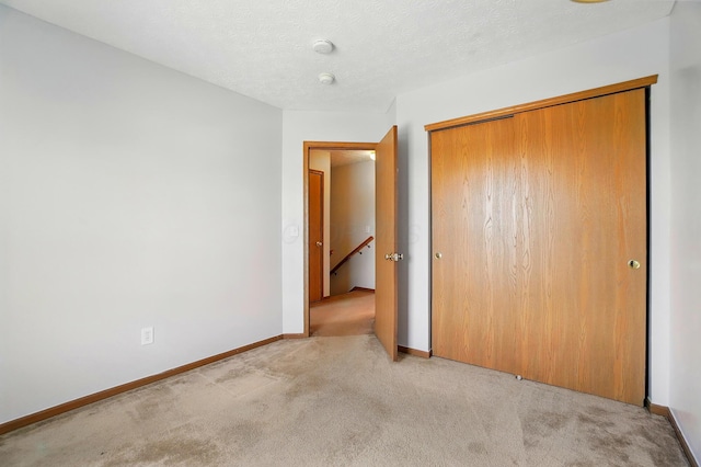 unfurnished bedroom with a closet, carpet flooring, and baseboards