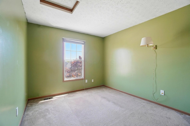 spare room featuring carpet flooring, a textured ceiling, visible vents, and baseboards