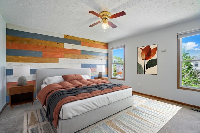 carpeted bedroom with wooden walls, baseboards, a textured ceiling, and visible vents