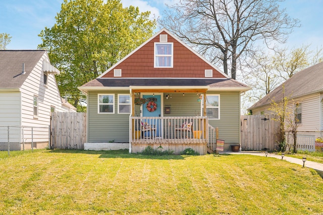 bungalow-style house featuring covered porch, fence, and a front lawn
