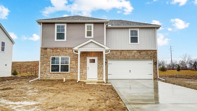 traditional-style home with a shingled roof, an attached garage, driveway, and stone siding