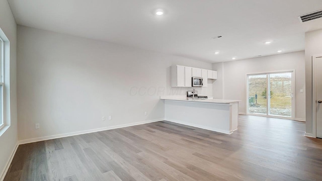 kitchen with light countertops, stainless steel appliances, visible vents, and wood finished floors