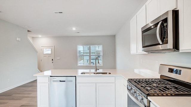 kitchen featuring visible vents, a sink, light countertops, a peninsula, and stainless steel appliances