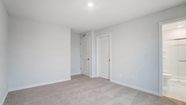unfurnished bedroom with carpet flooring, baseboards, visible vents, and ensuite bath