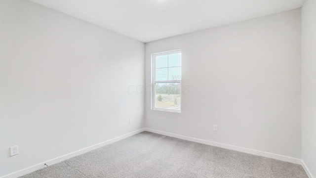 unfurnished room featuring baseboards and light carpet