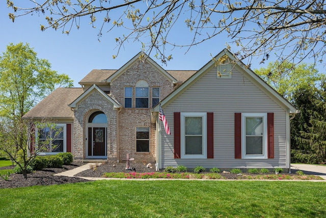 view of front of home featuring brick siding, a front lawn, and roof with shingles