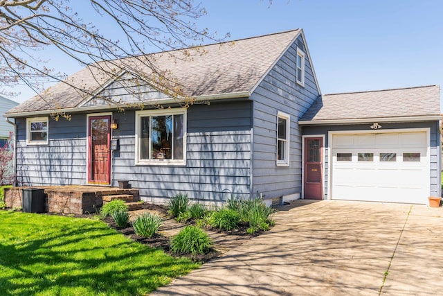 single story home with concrete driveway, an attached garage, a shingled roof, and a front lawn